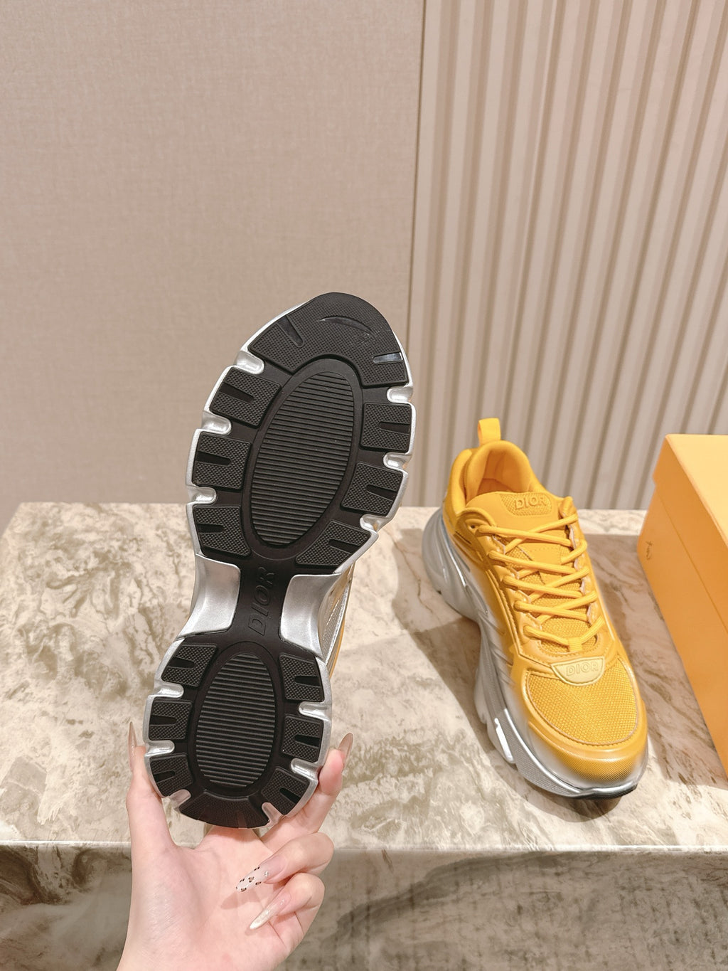 Dior unisex sneakers outsole view, black tread soles with yellow uppers