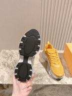 Dior unisex sneakers outsole view, black tread soles with yellow uppers