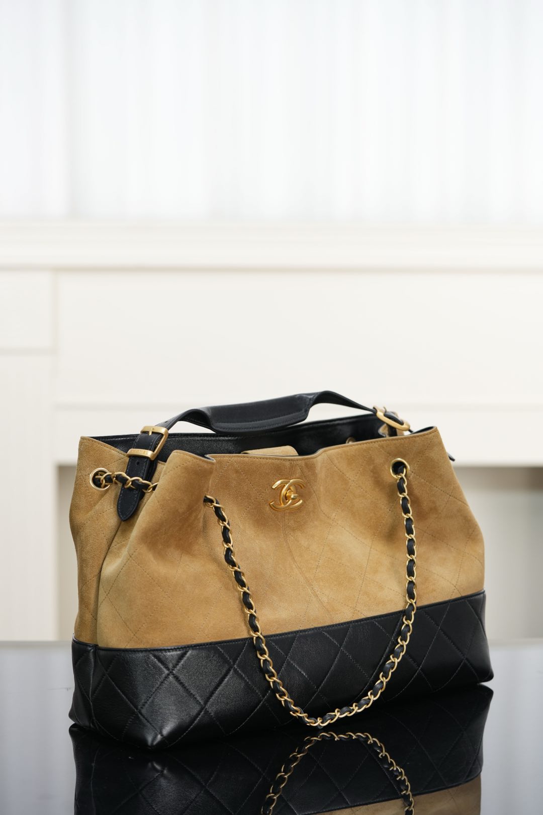 Two-tone Chanel tote bag with tan suede-style top, quilted black base, chain shoulder handles.