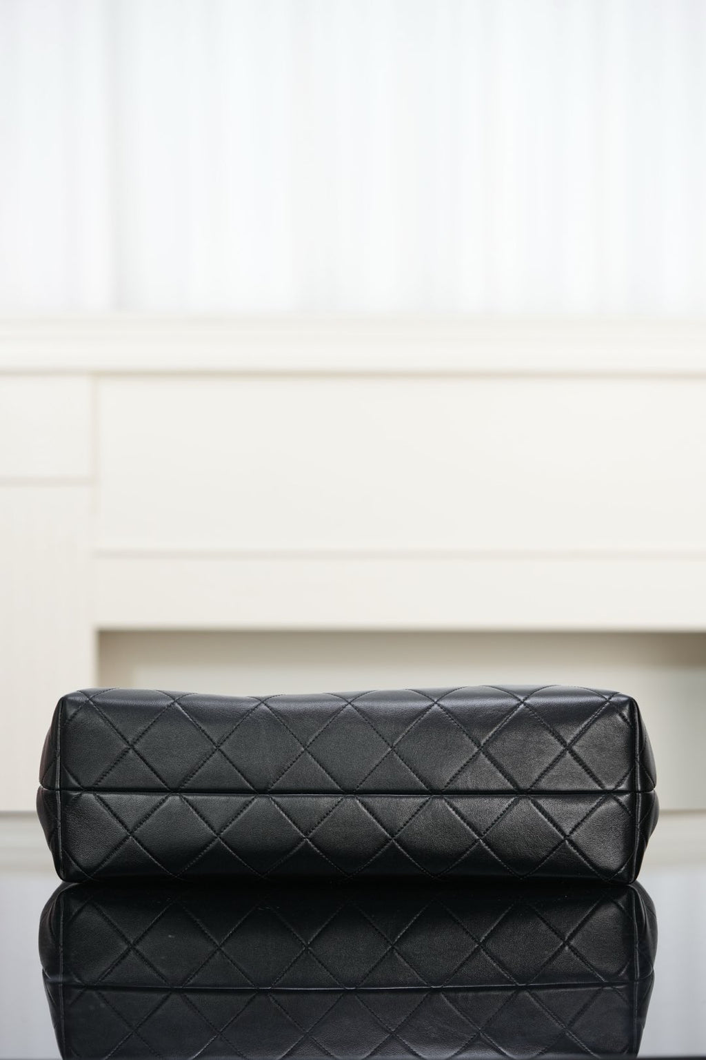 Black quilted bag with diamond stitching and padded top flap, gold-tone details.