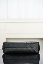 Black quilted bag with diamond stitching and padded top flap, gold-tone details.