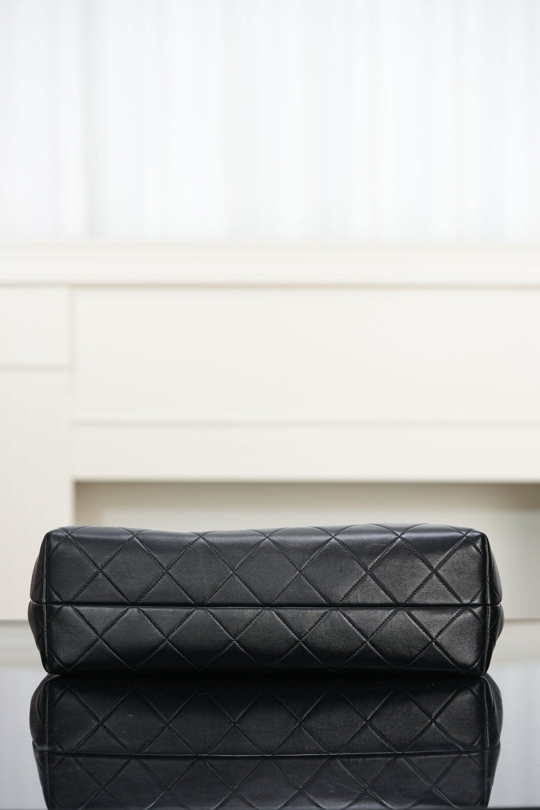 Black quilted bag with diamond stitching and padded top flap, gold-tone details.