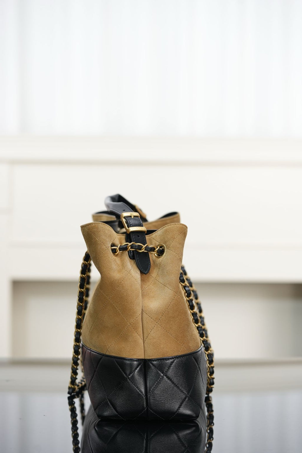 Back view of two-tone Chanel tote with tan panel, quilted black base, chain straps.