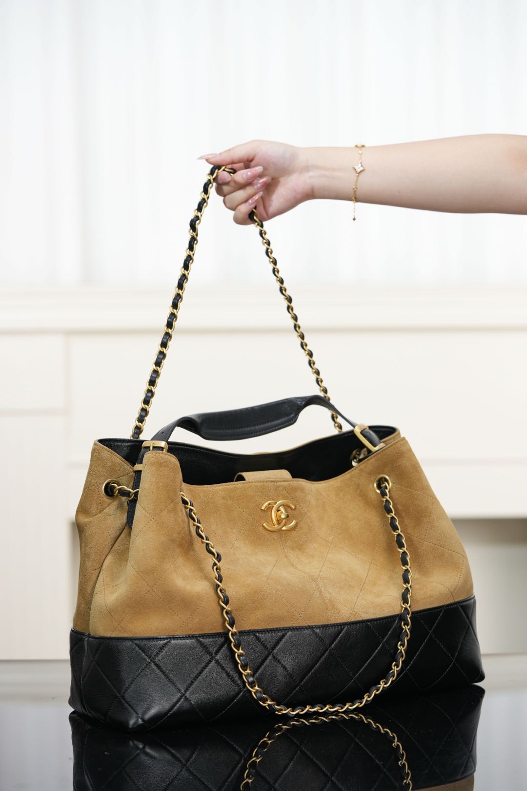 Two-tone Chanel tote with tan front, quilted black lower section, gold chain straps.