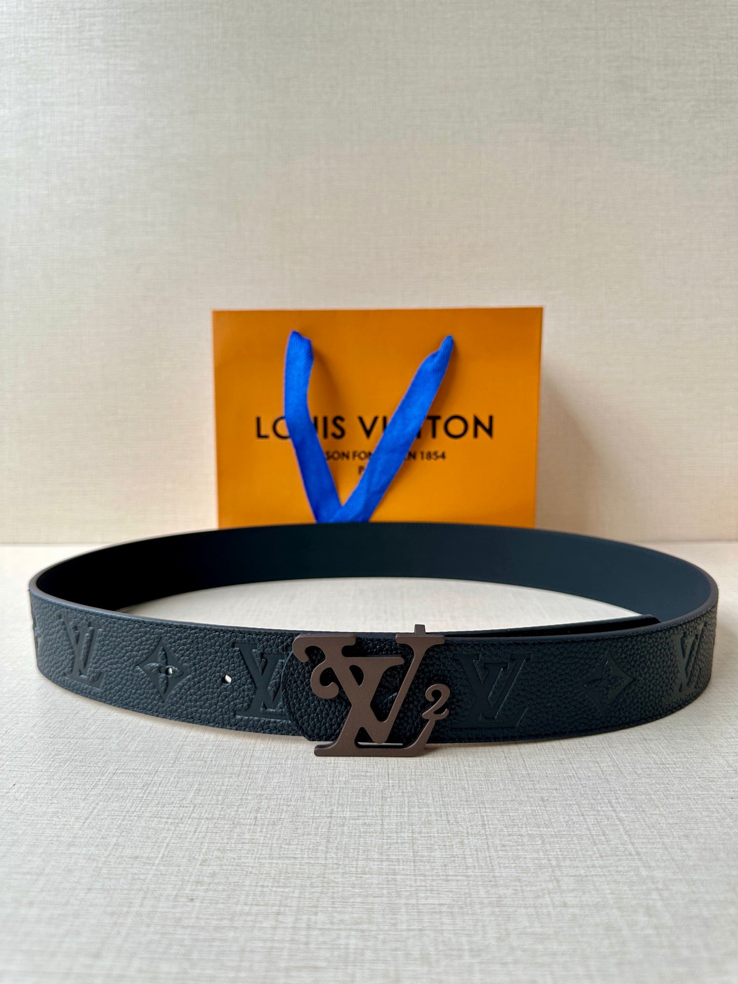 Black textured leather belt with embossed monogram and metal LV buckle