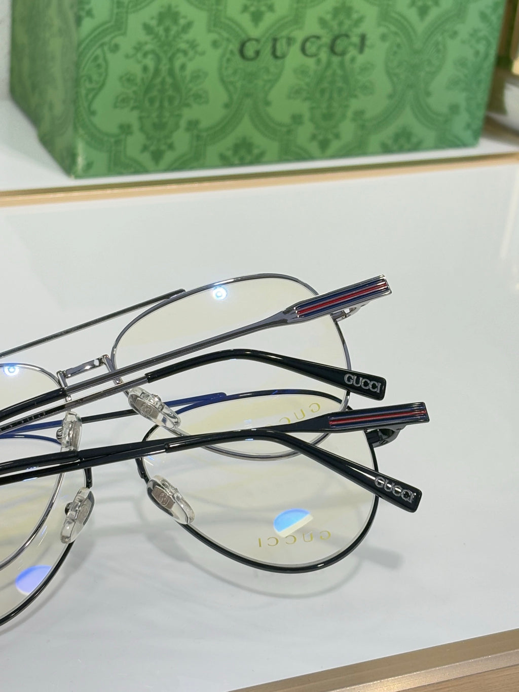 Gucci eyeglasses set with thin metal frames and blue-red striped temple details