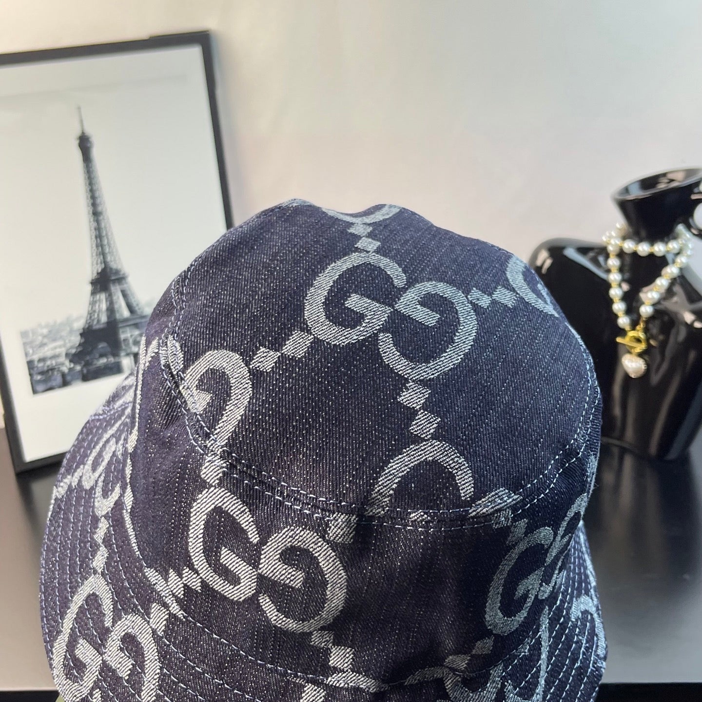 Gucci bucket cap showing side view of dark denim with GG monogram pattern