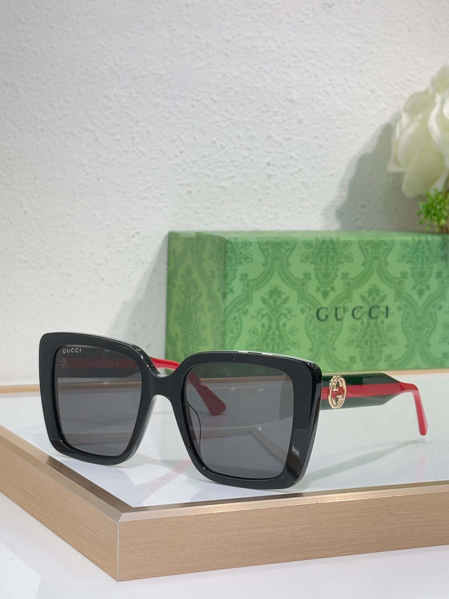 Black square sunglasses with gray lenses and red/green temple accents.