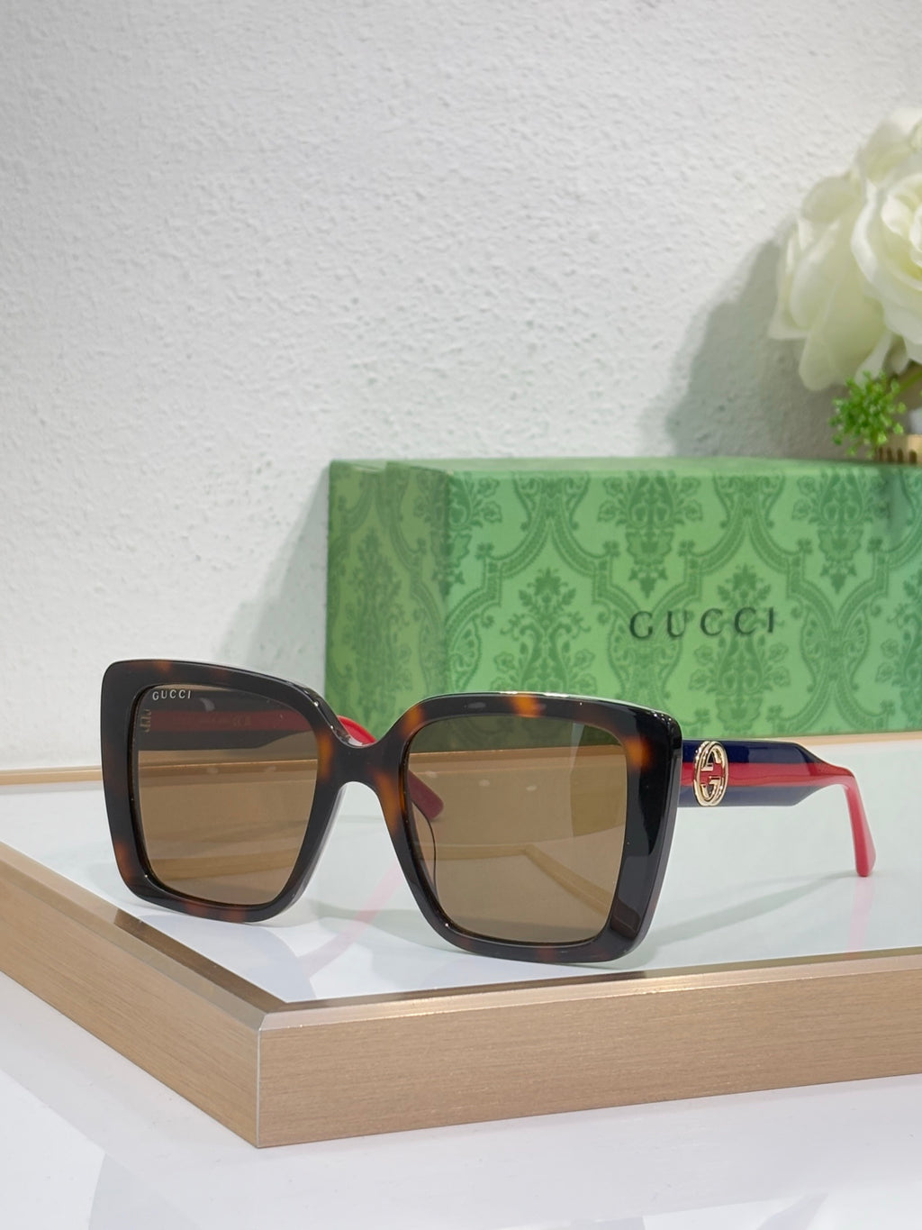 Brown-tinted square sunglasses with tortoise frame and red/green temple stripe.