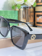 Black square sunglasses with gray lenses and gold Gucci logo on the temple.