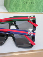 Gucci-style sunglasses with red, green, and blue striped temples and logo emblems.