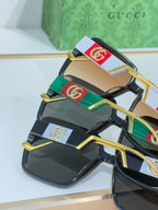 Gucci sunglasses close-up with dark lenses and gold metal logo temples