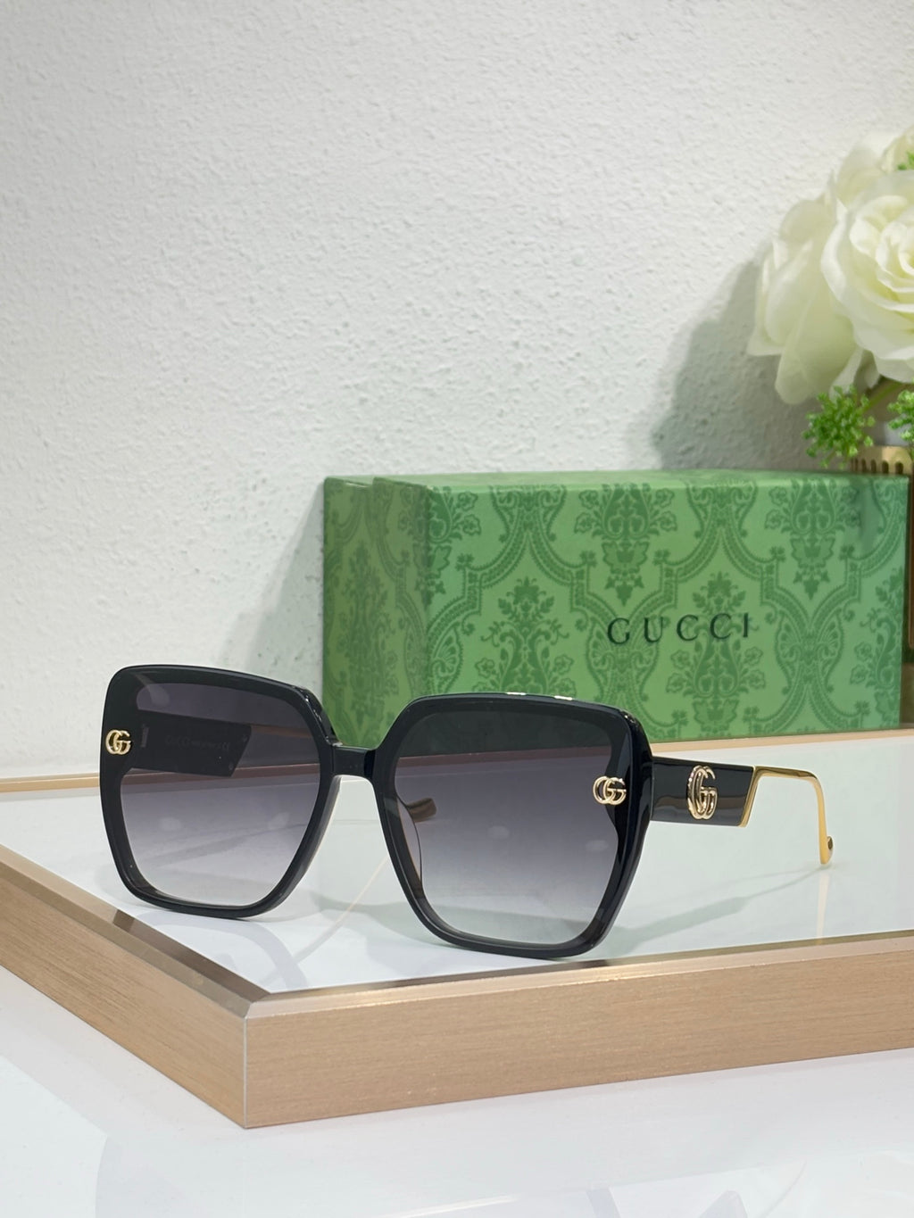 Gucci sunglasses with black frame, dark lenses, and gold GG logo details