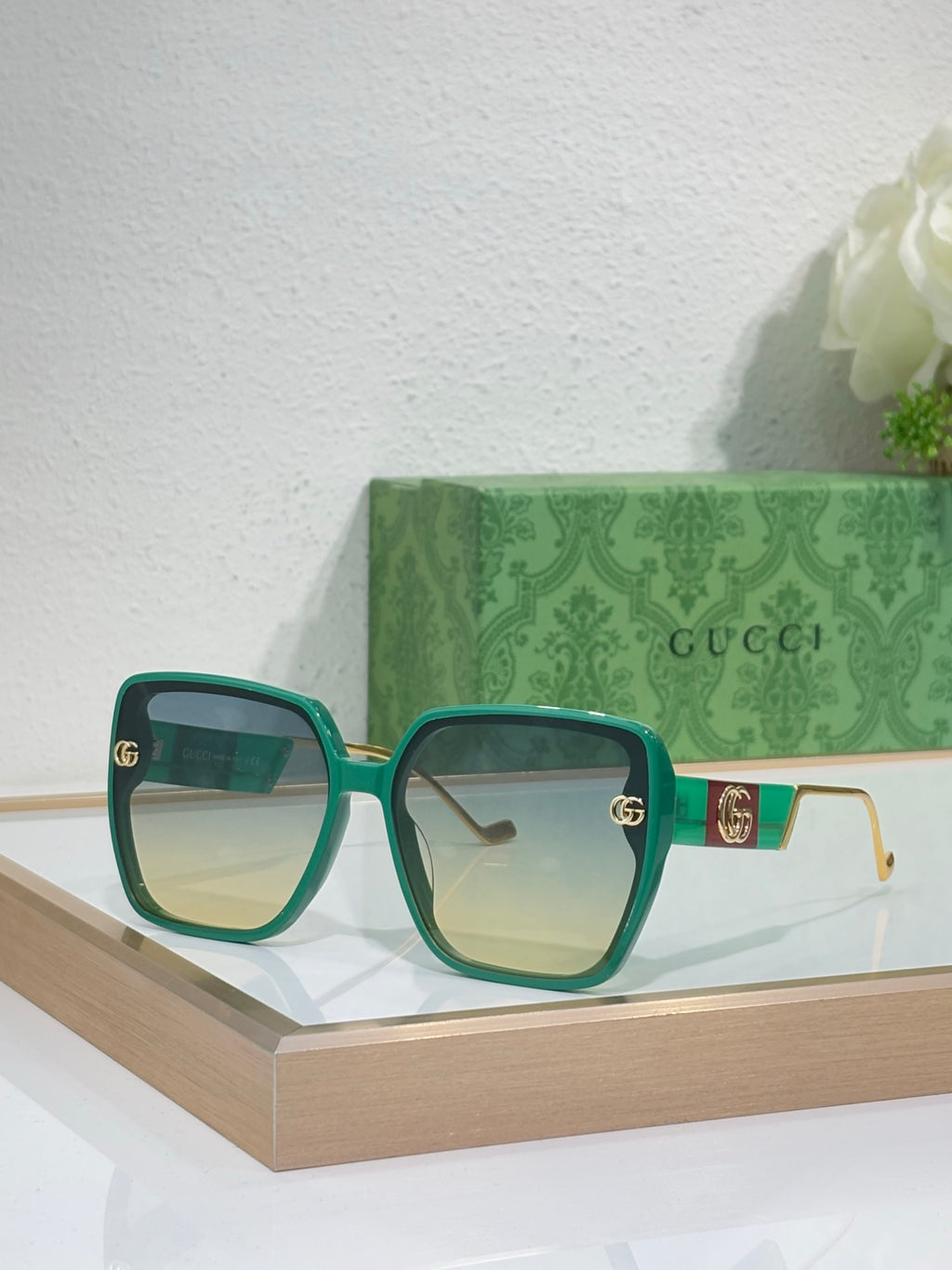 Gucci sunglasses with green frame, light gradient lenses, and gold GG details