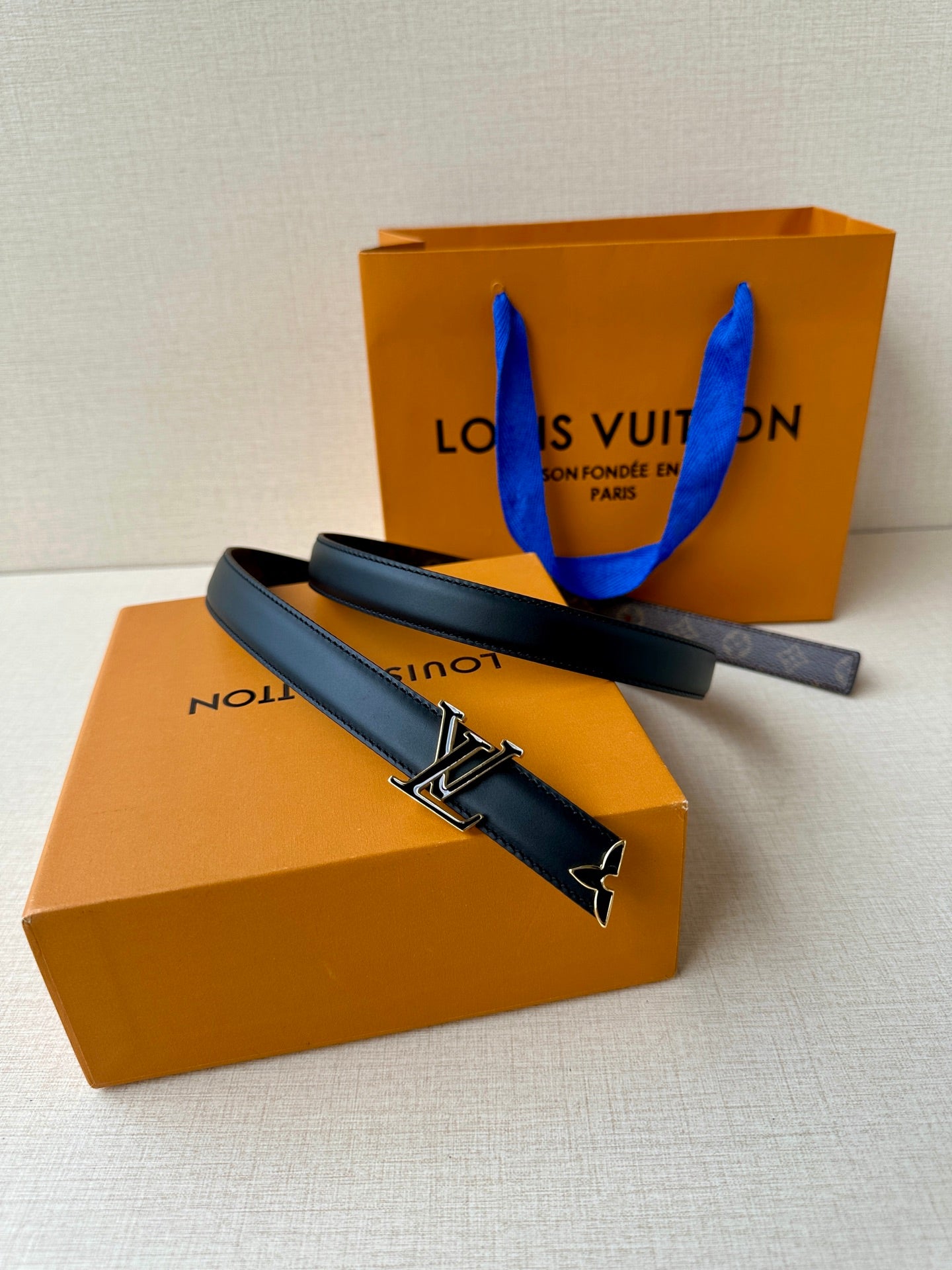 Louis Vuitton belt with dark blue leather strap and gold-tone LV buckle, laid flat