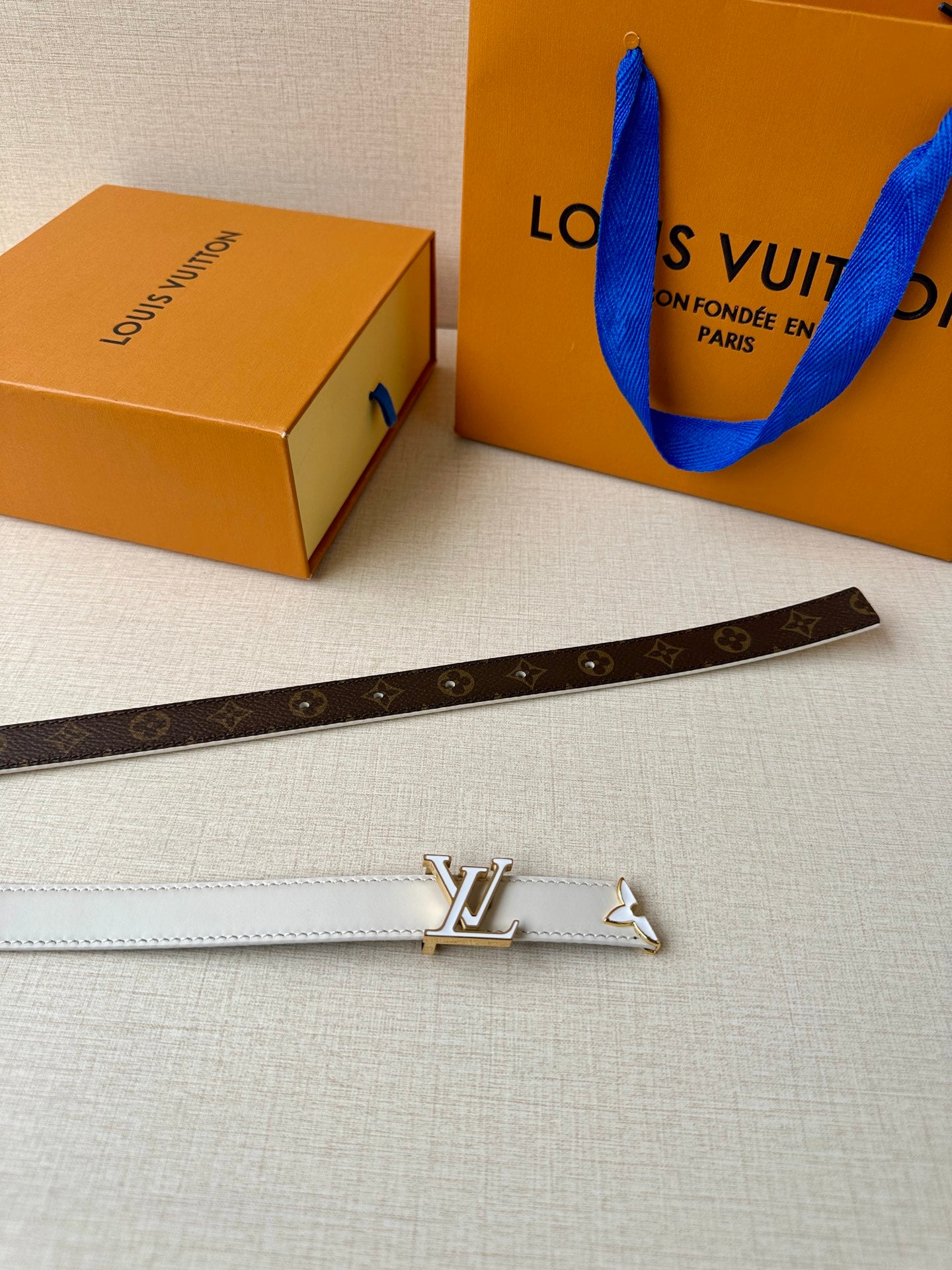 Brown monogram belt with white edge trim and gold-tone LV buckle.