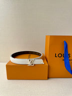 White leather belt with gold-tone LV buckle over dark monogram strap.