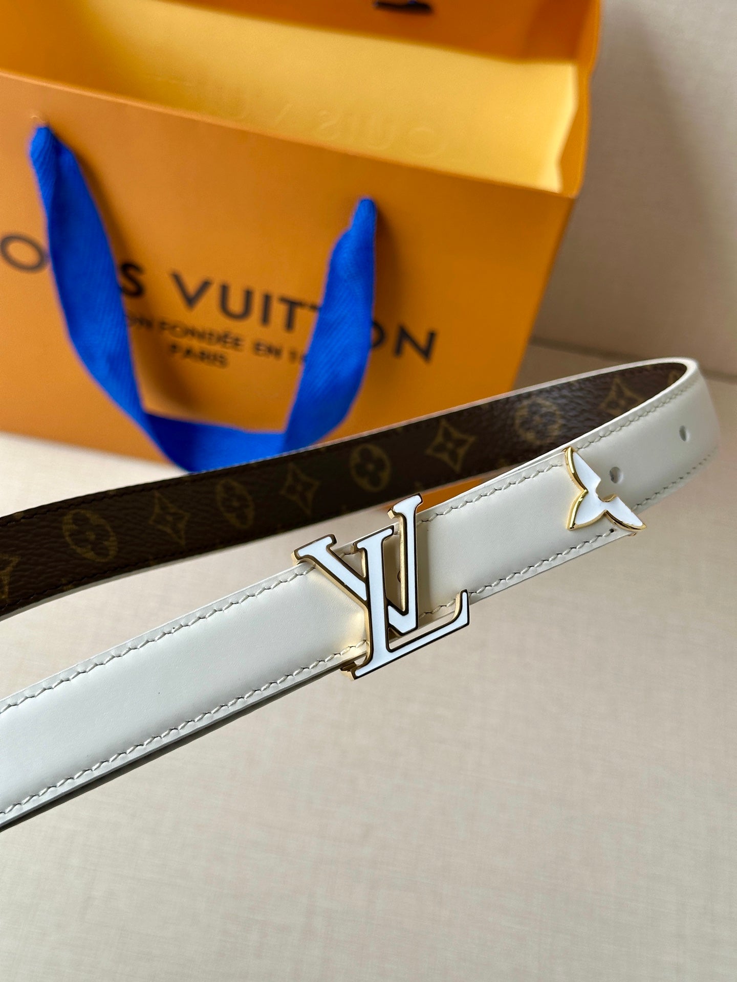 Monogram and white leather belt with large gold-tone LV buckle.