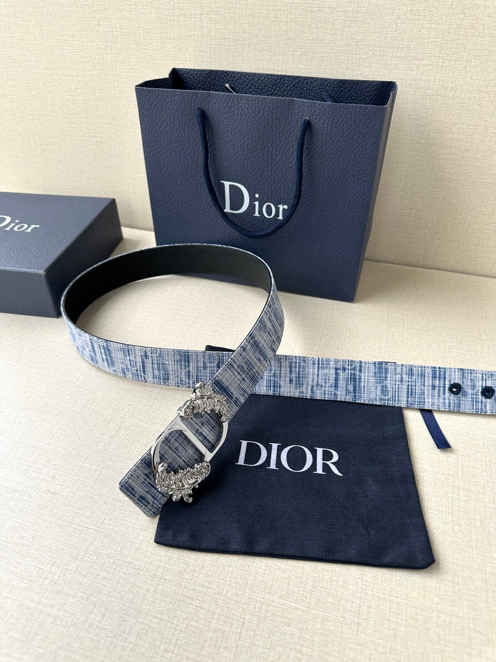 Dior belt with blue textured strap and gold buckle, with navy dust bag and box