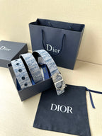 Dior belt in box with blue patterned strap and ornate gold buckle on navy pouch