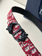 Dior belt close-up: red monogram strap with black buckle and floral appliqué.
