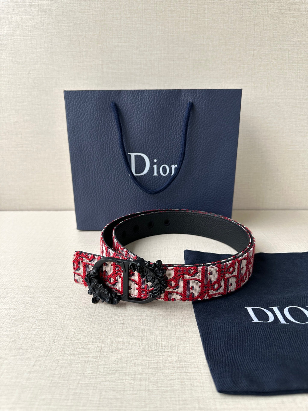 Dior belt with red monogram strap and black buckle on adjustable leather belt.