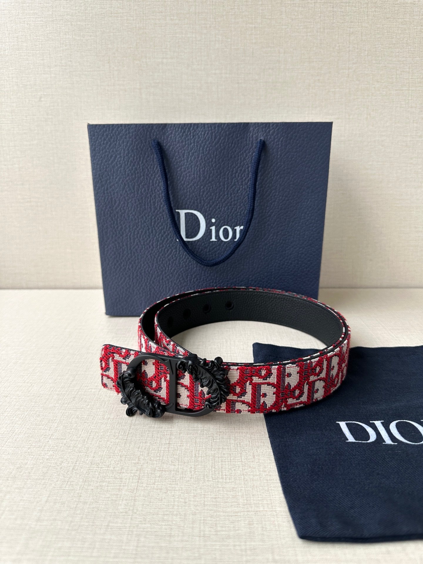 Dior belt with red monogram strap and black buckle on adjustable leather belt.
