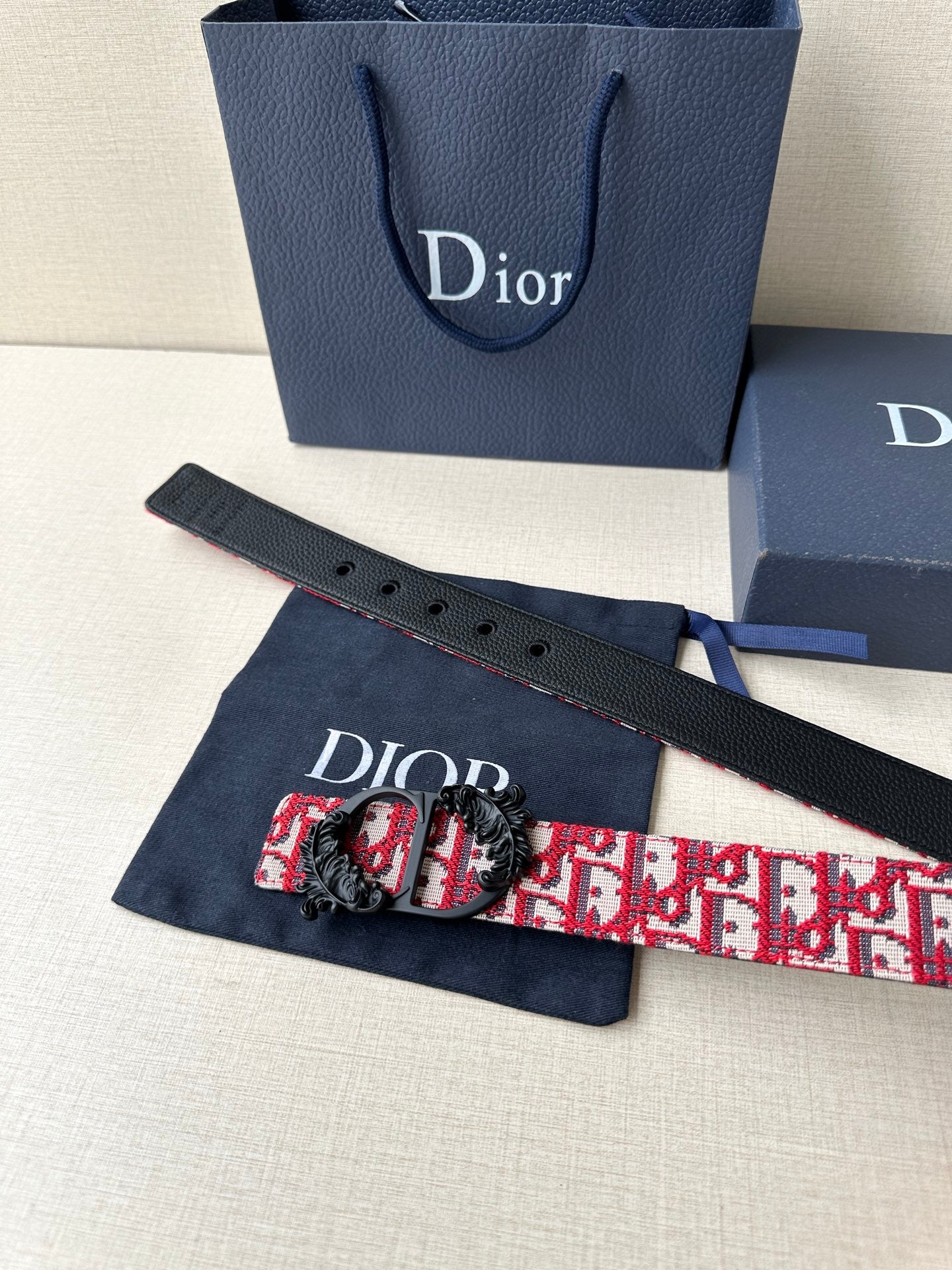 Dior belt with red Dior pattern strap, black belt holes, and decorative buckle.