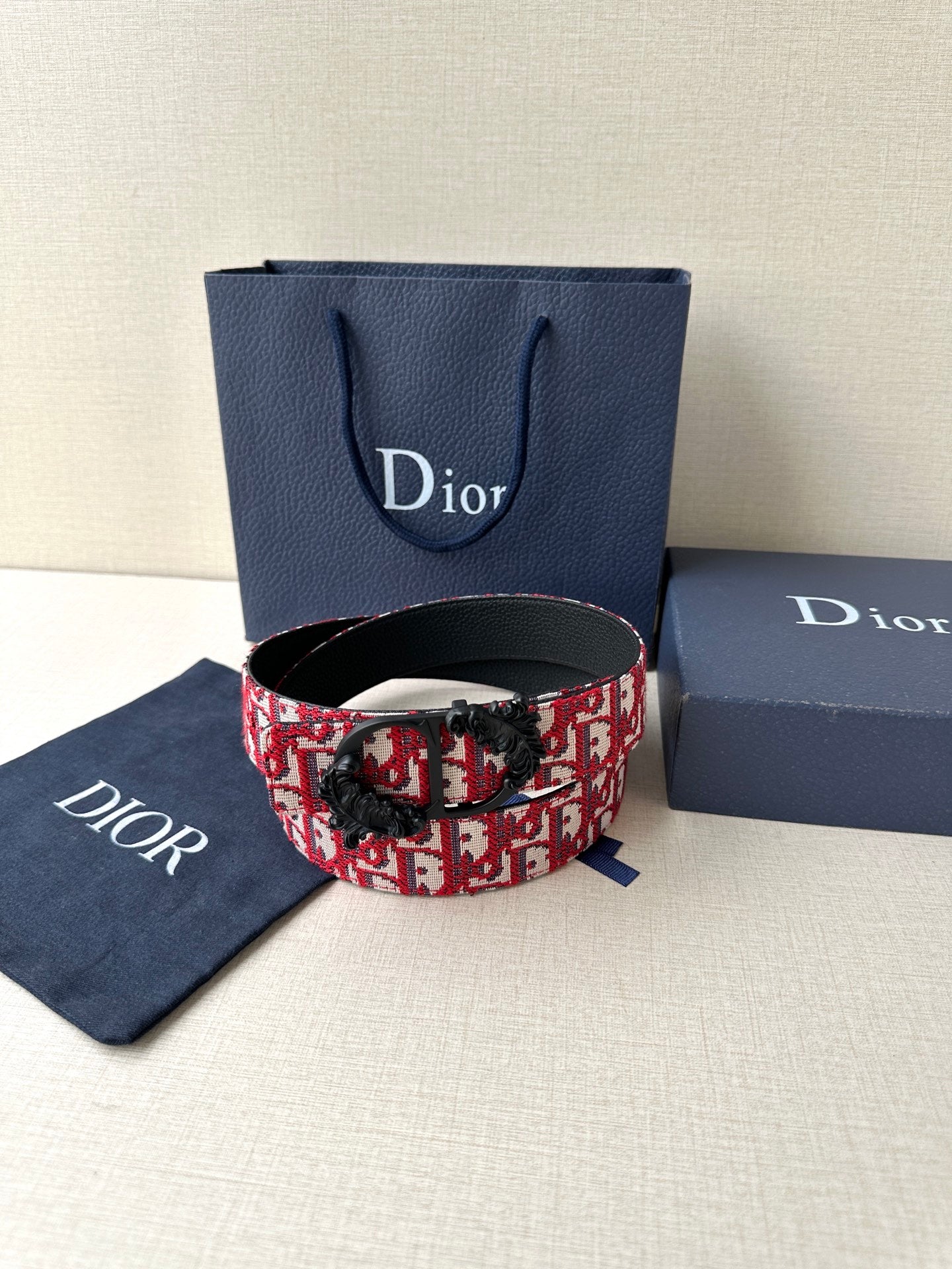 Dior belt display: red-and-black monogram strap with black buckle and clasp.
