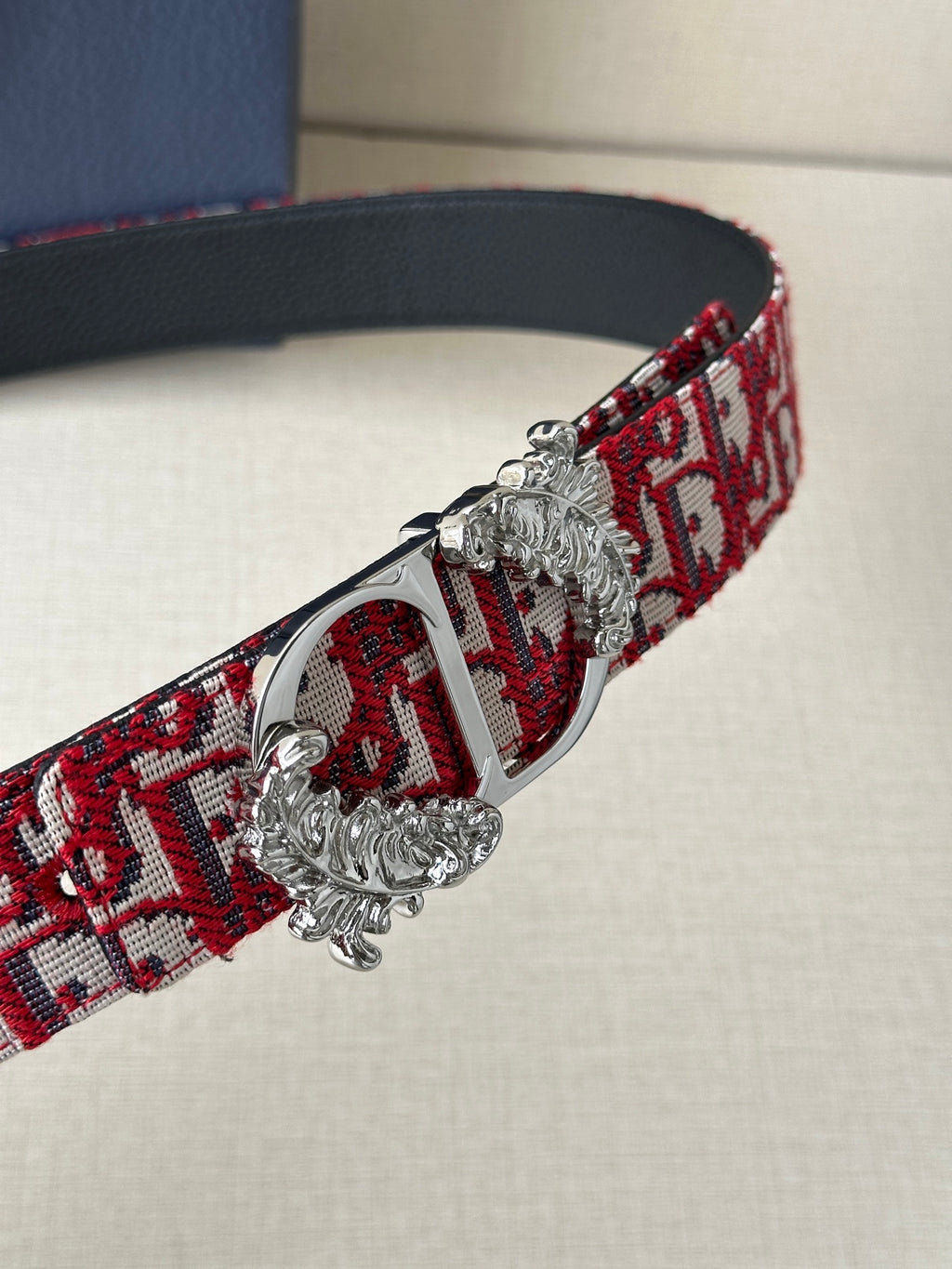 Red patterned belt with ornate silver-tone buckle and black leather edge