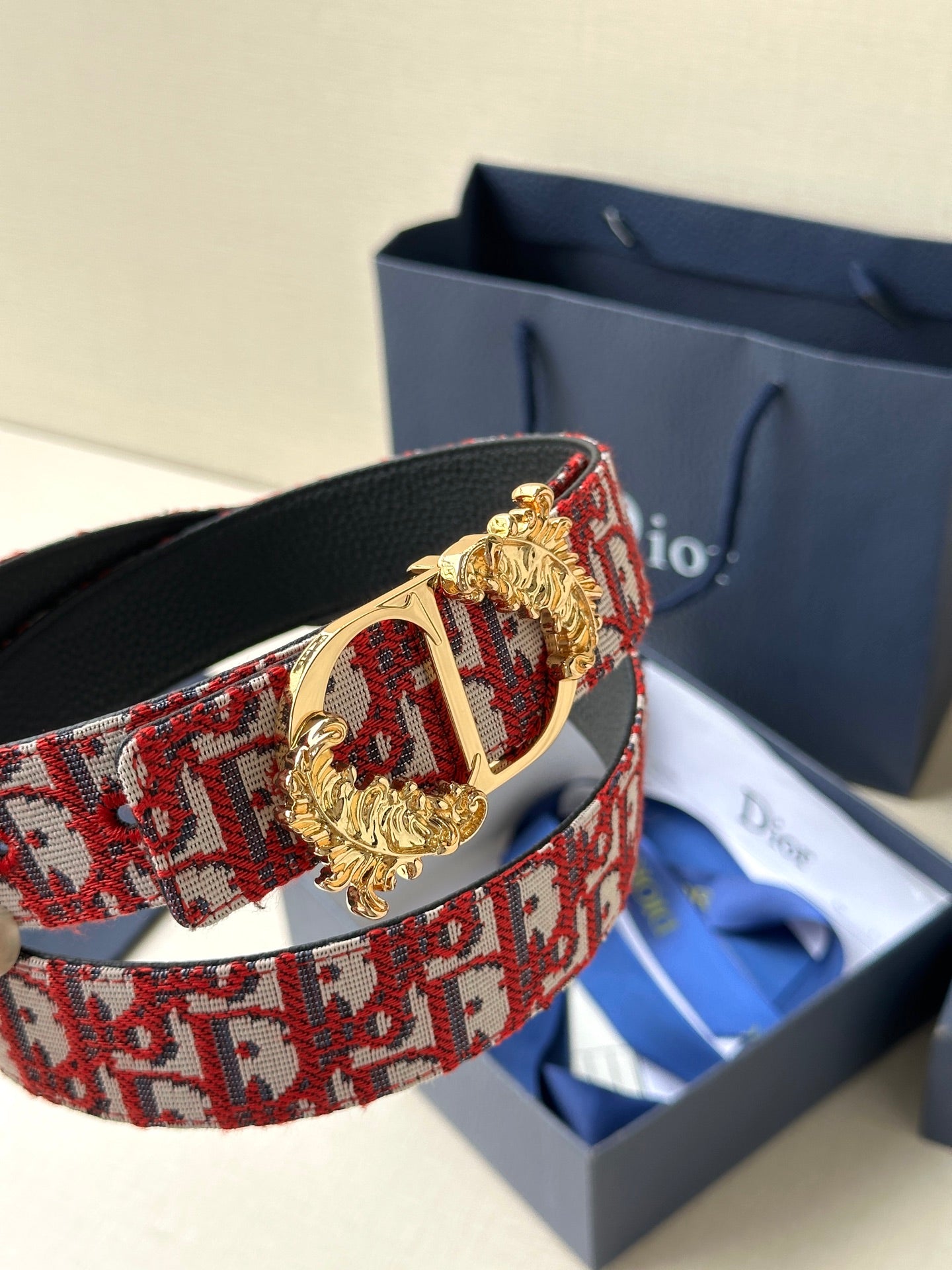 Red monogram belt with gold-tone lion-head buckle and black leather strap