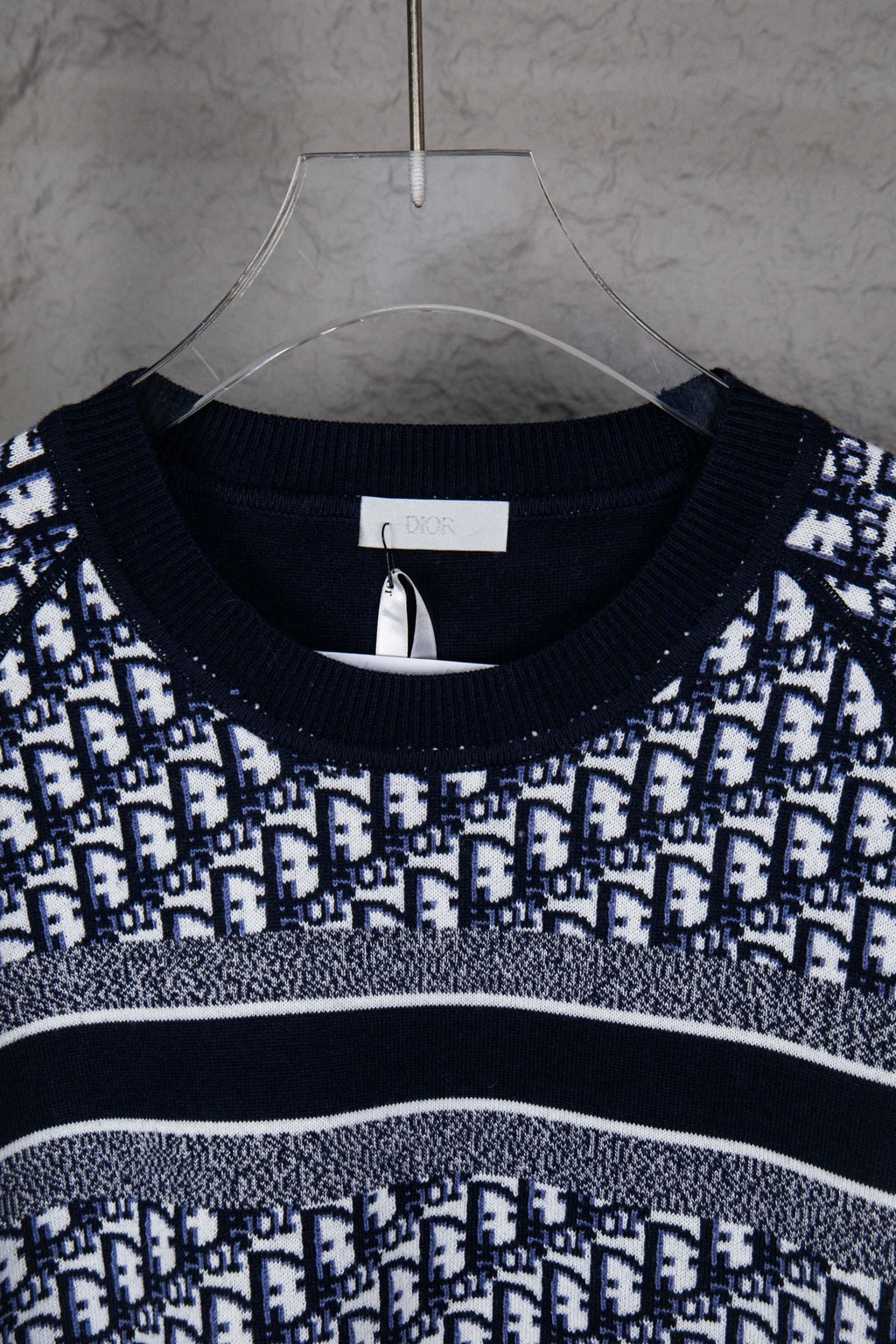 Neckline close-up of knit sweater with navy rib trim and monogram pattern