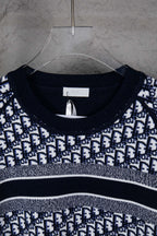 Neckline close-up of knit sweater with navy rib trim and monogram pattern