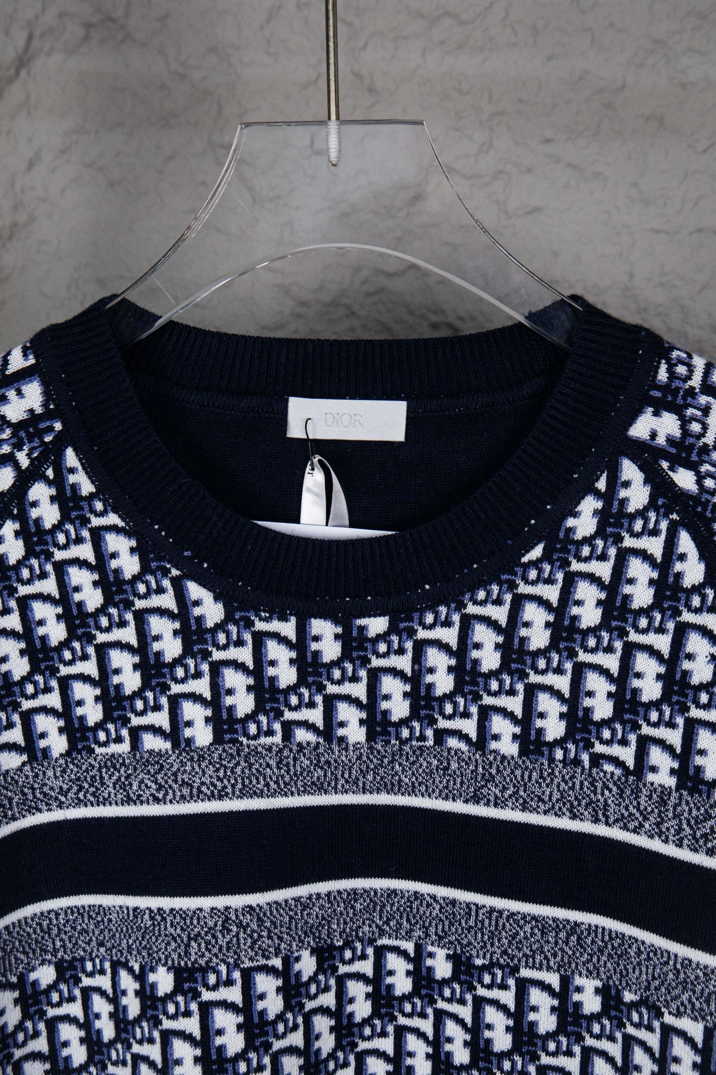 Neckline close-up of knit sweater with navy rib trim and monogram pattern
