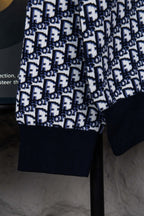 Sleeve and hem detail of knit sweater with monogram pattern and navy cuffs