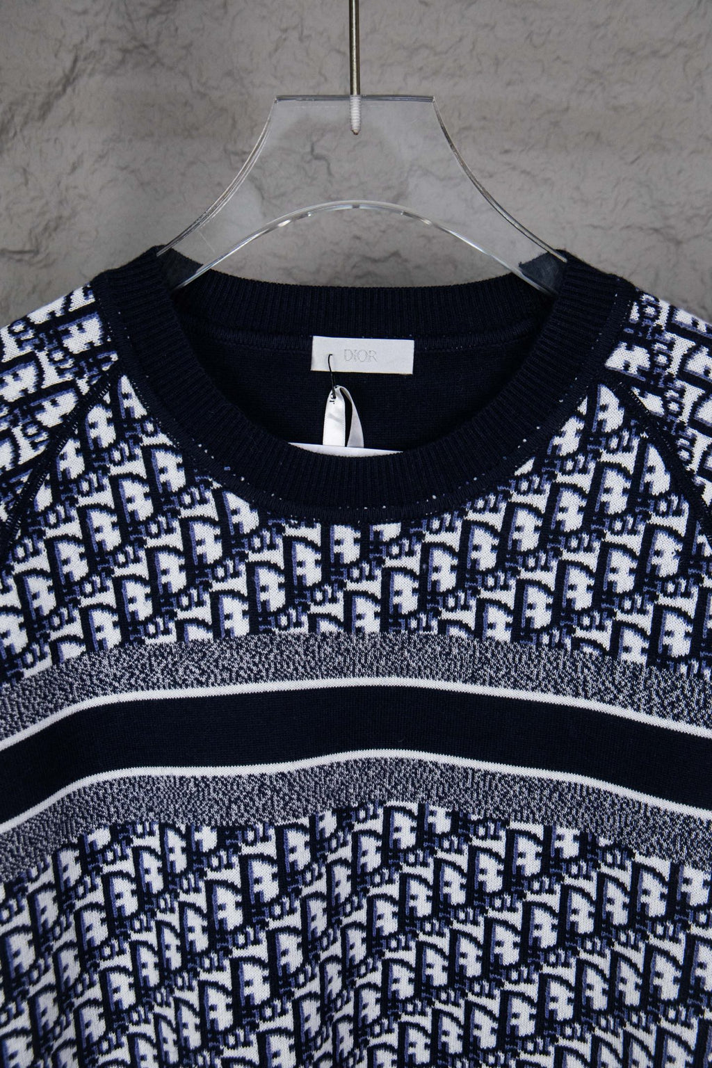Round-neck knit sweater with navy and white monogram pattern across the chest