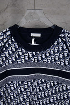 Round-neck knit sweater with navy and white monogram pattern across the chest