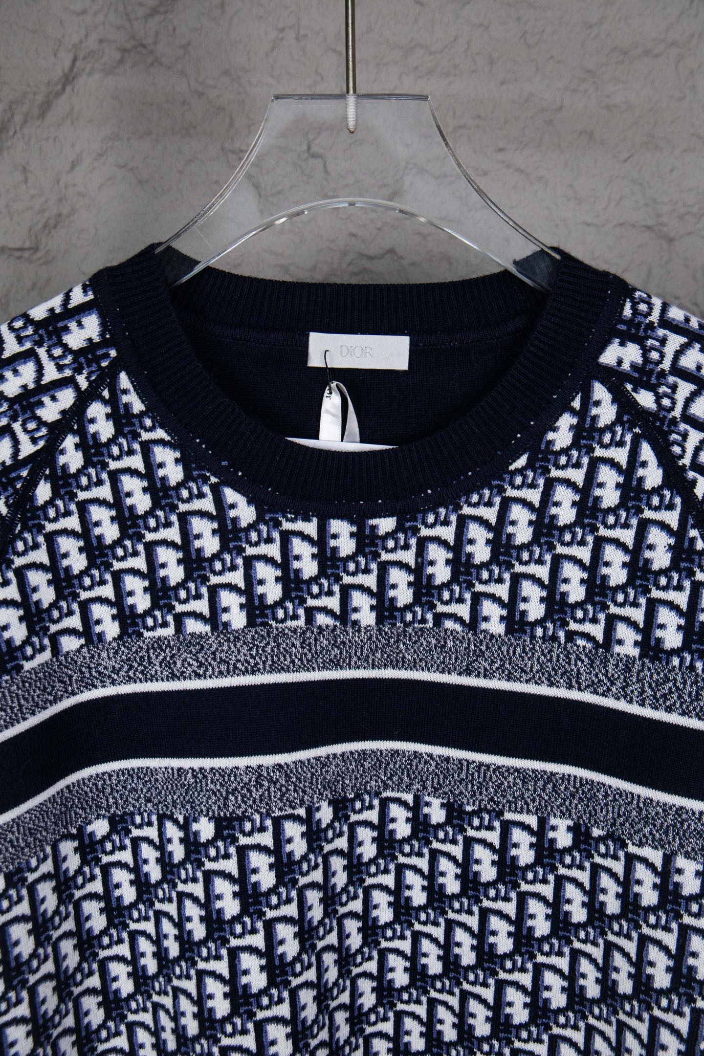 Round-neck knit sweater with navy and white monogram pattern across the chest