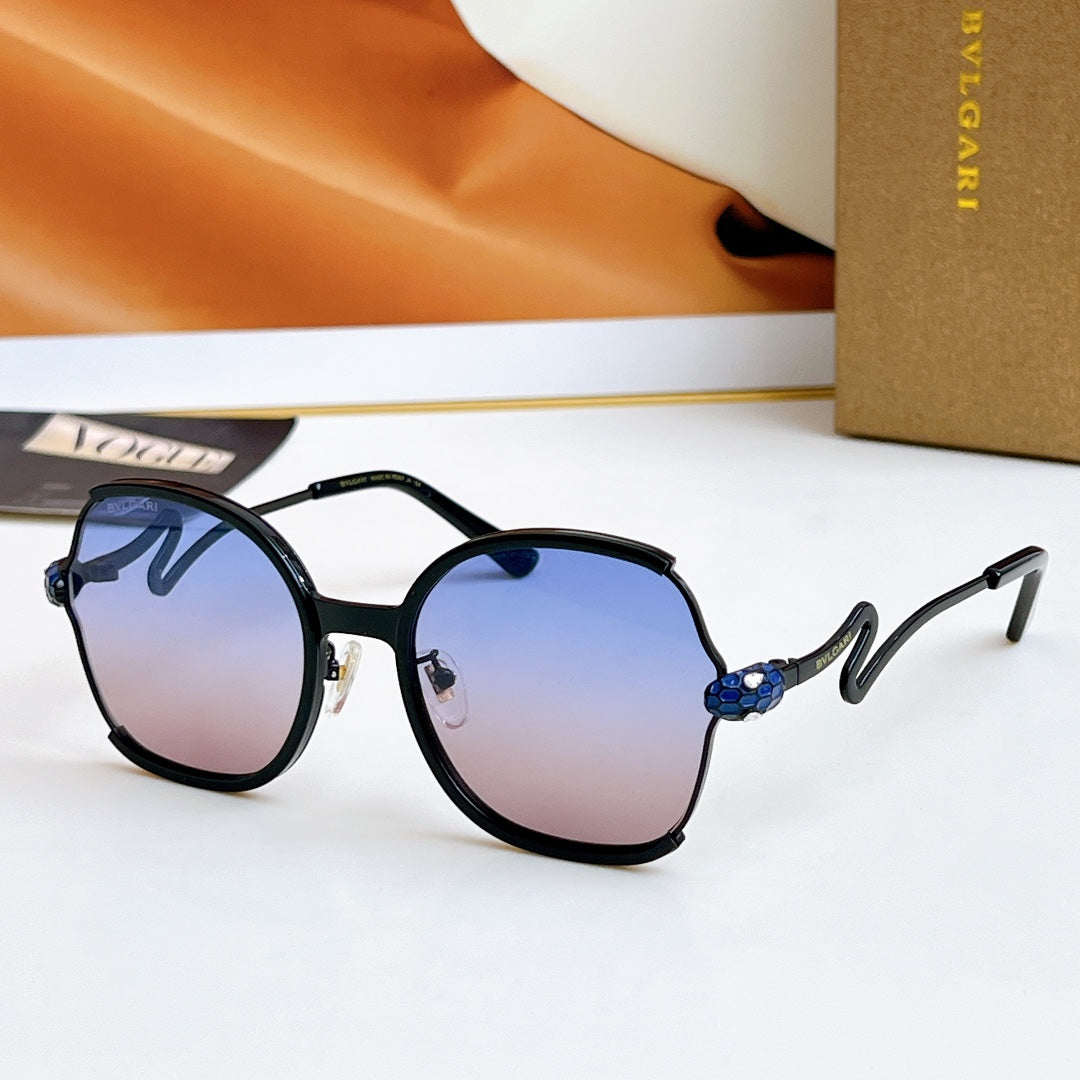 Sunglasses with black frames and gold-tone arms, blue jewel detail, dark lenses