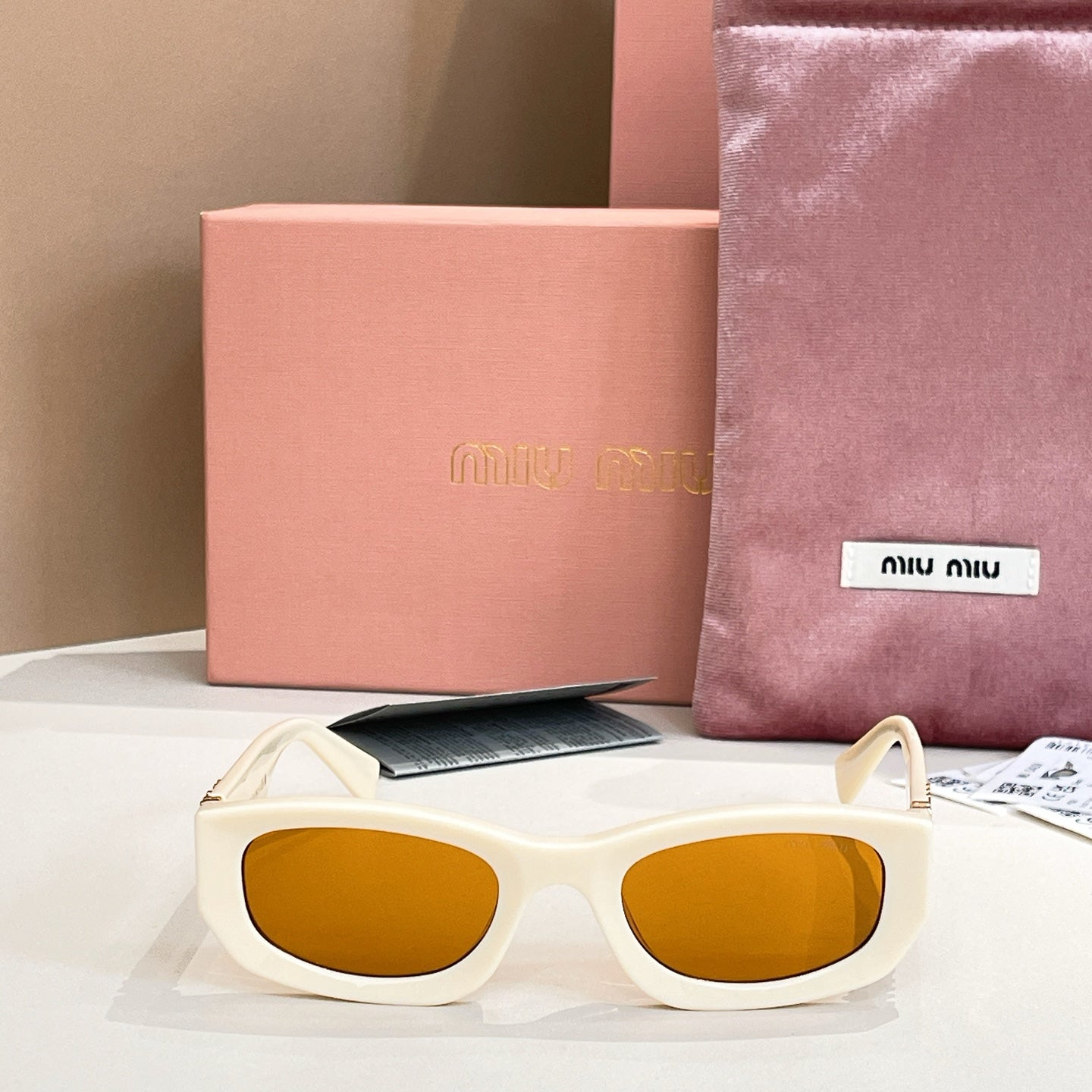 MiuMiu cream sunglasses with amber mirrored lenses and gold-tone logo arms