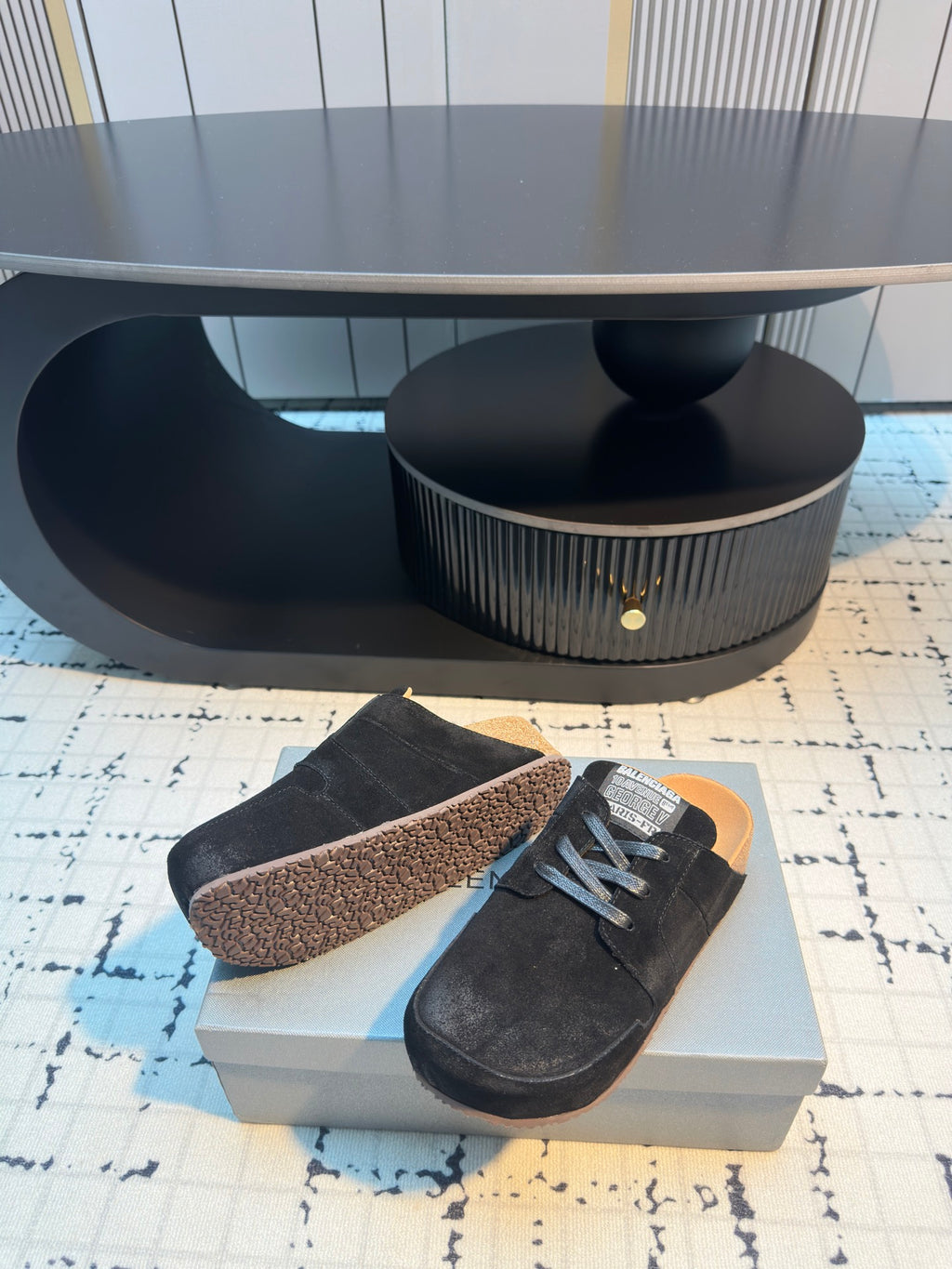 Balenciaga black lace-up slip-on shoes, one shoe showing tan textured outsole.