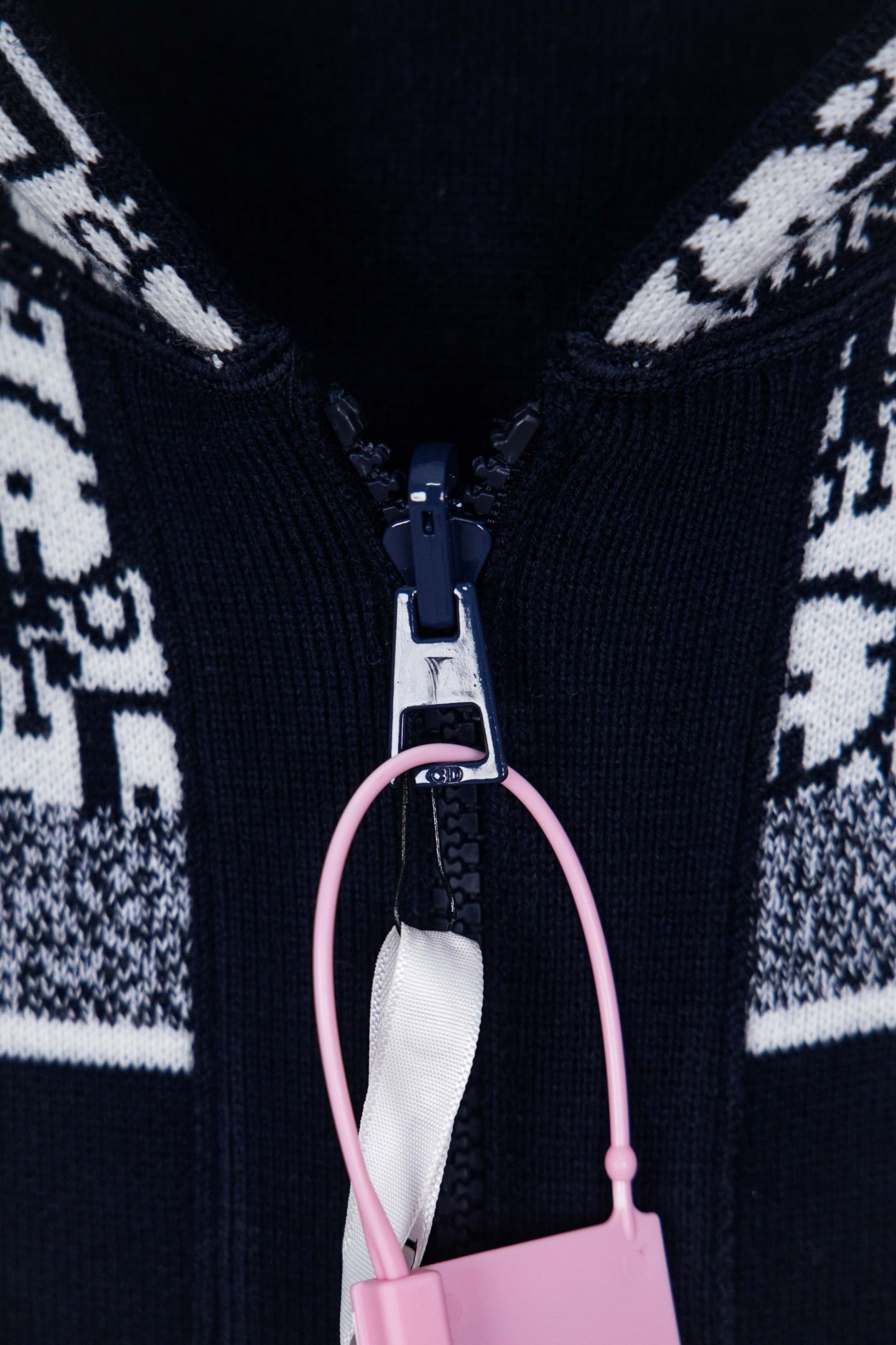 Dior knit jacket zipper close-up with pink pull charm and ribbed knit edges