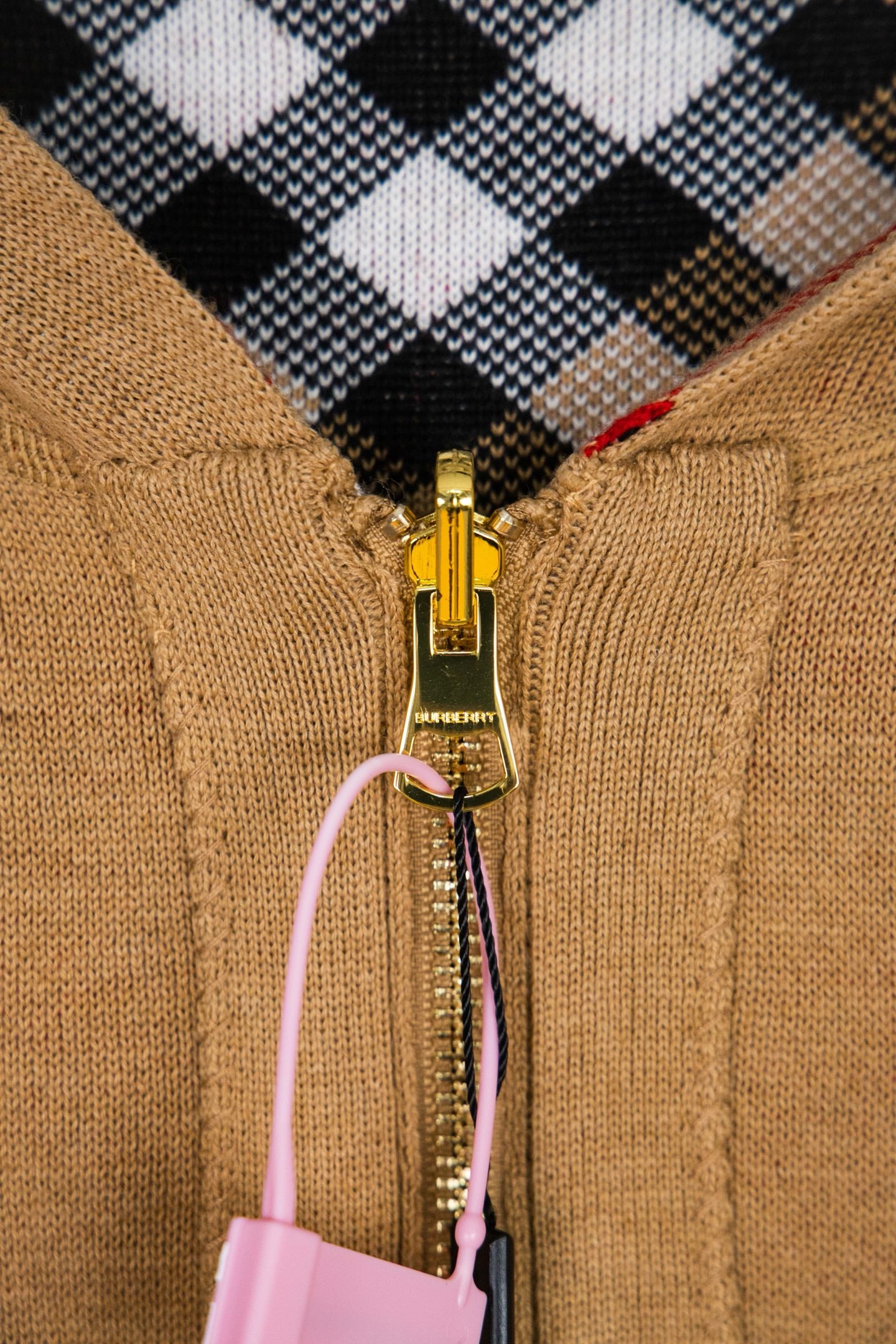 Burberry tan jacket zipper close-up with check lining and dangling charm