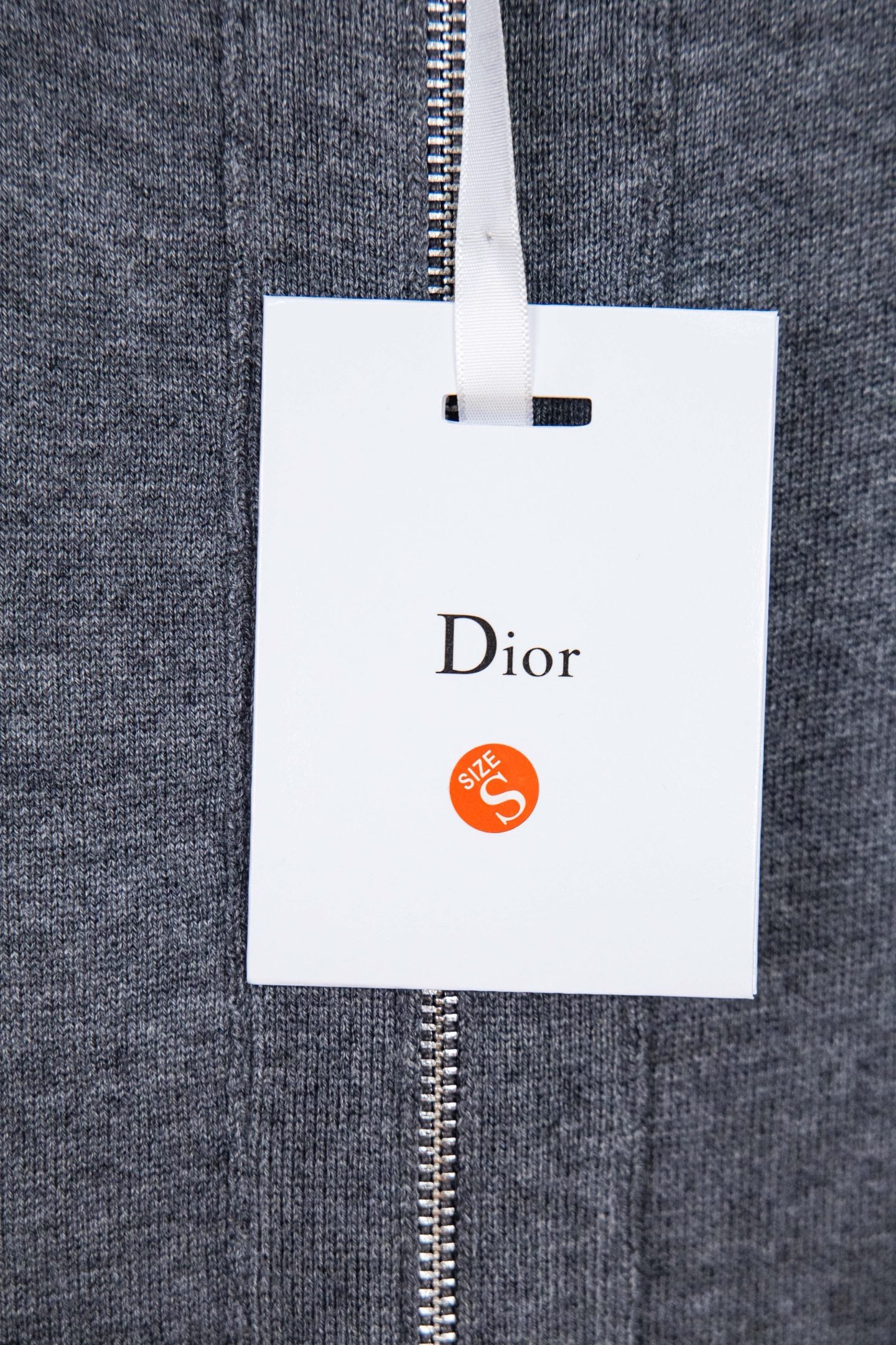 Heather gray zip hoodie with hanging white Dior tag on zipper