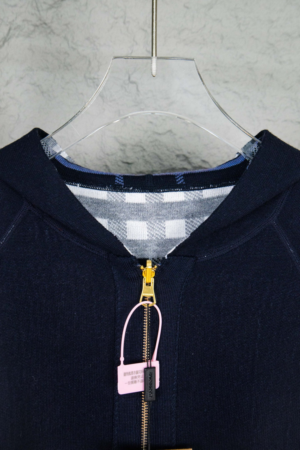 Close-up of navy hooded zip-up knit jacket, front zipper and check-lined hood