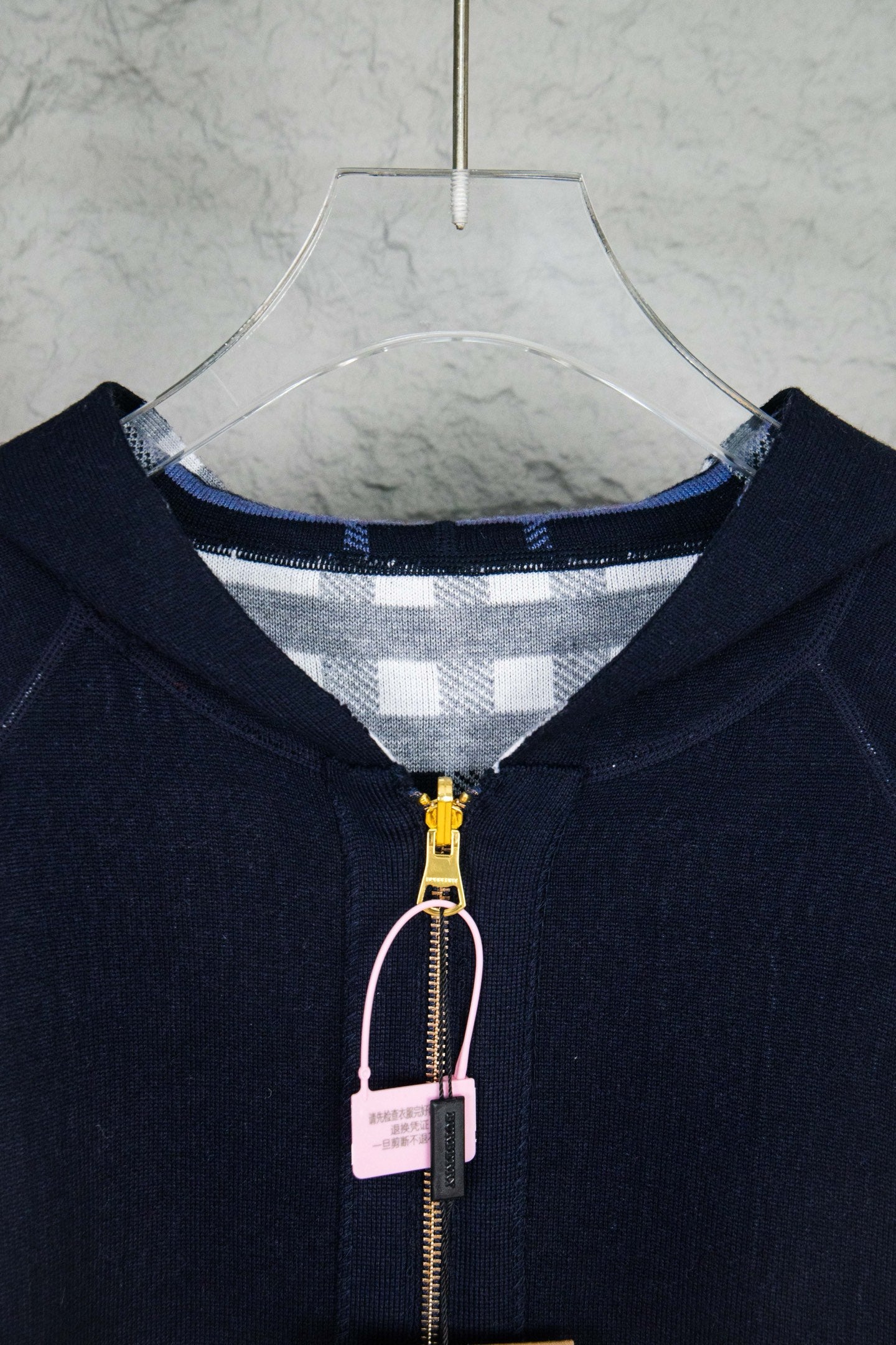 Close-up of navy hooded zip-up knit jacket, front zipper and check-lined hood