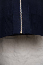 Bottom front close-up of navy hooded zip-up knit jacket with gold zipper teeth
