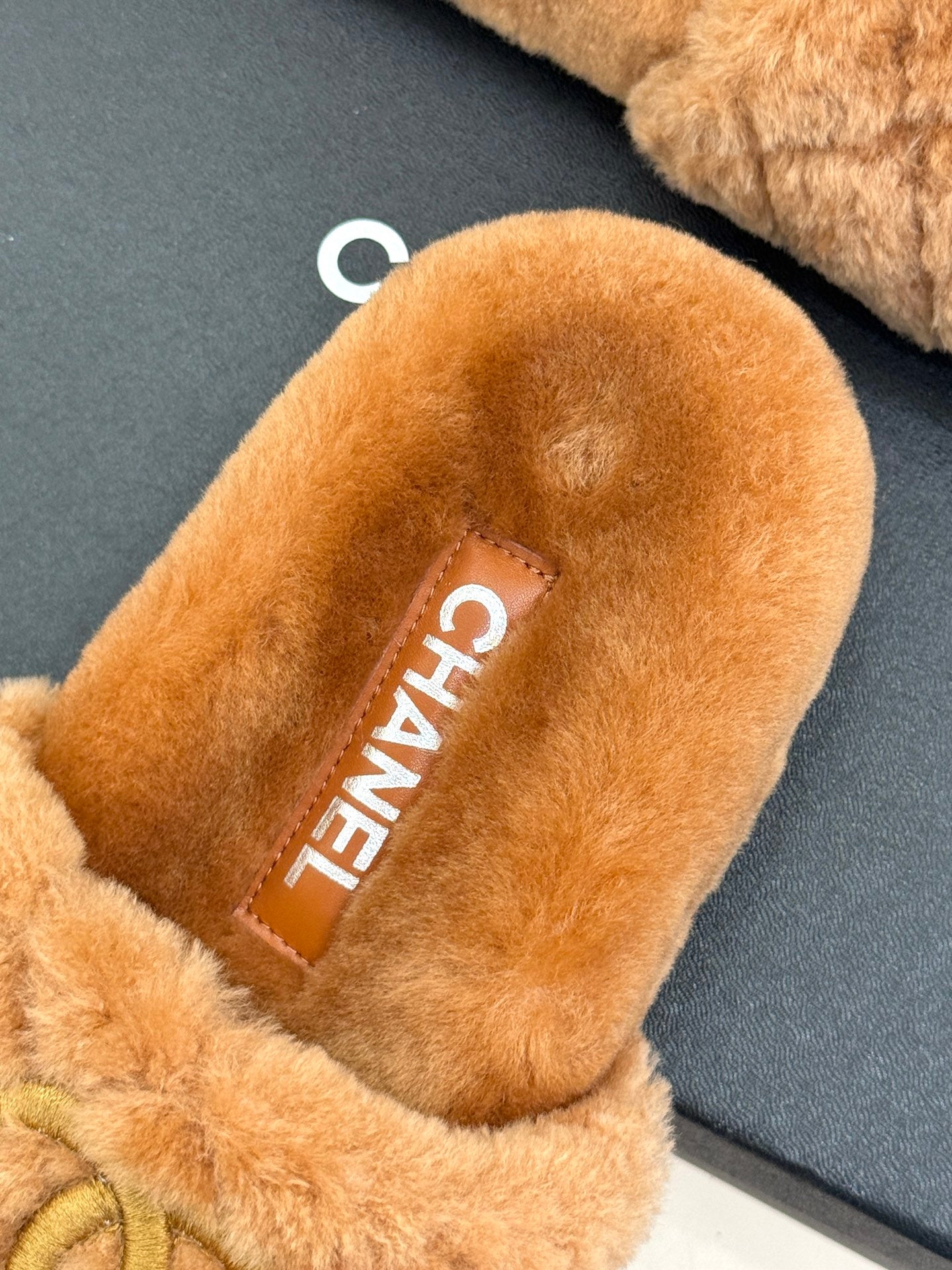 Close-up of tan Chanel fuzzy slide slipper interior with CHANEL label