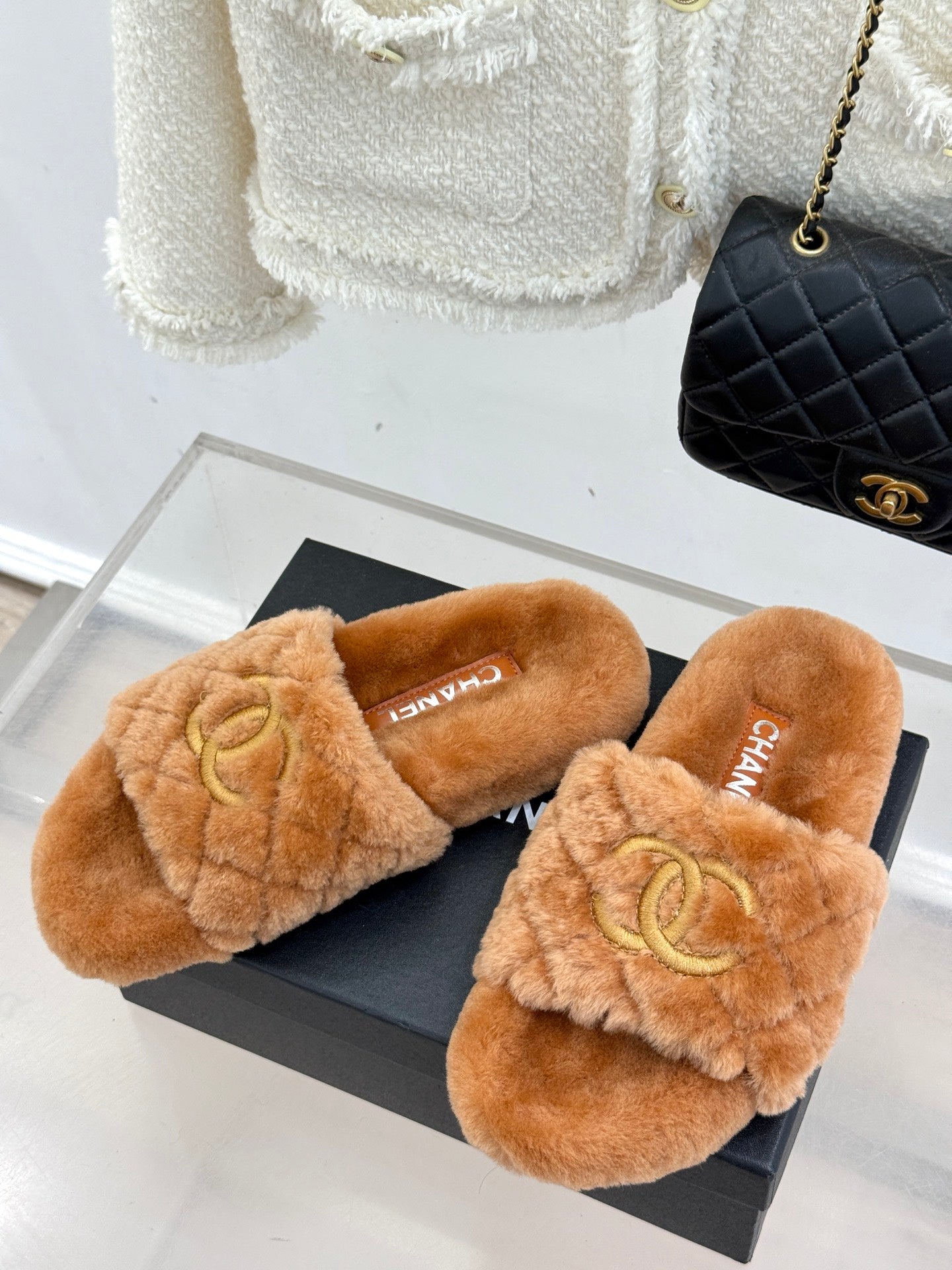 Pair of tan Chanel fuzzy slide slippers on a box, Double C logo on uppers