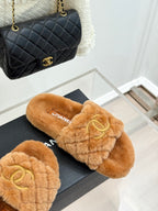 Tan Chanel fuzzy slide slippers on a box, with gold Double C on the strap